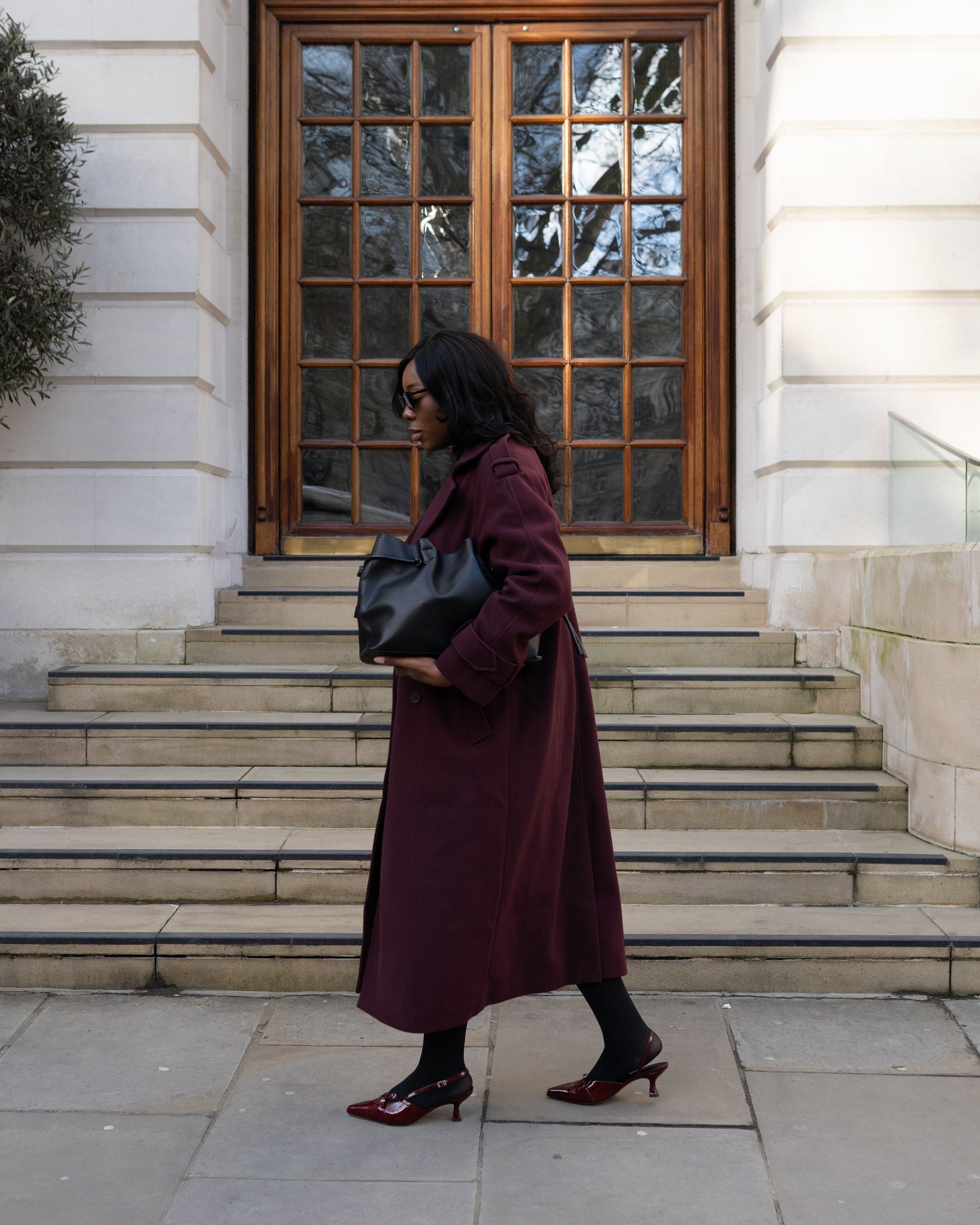 Woman in a burgundy coat walking wearing burgundy wide fit kitten heels